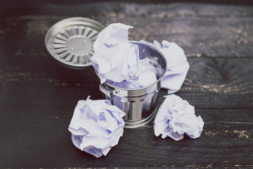 garbage bin on desk setting with scrunched paper balls inside