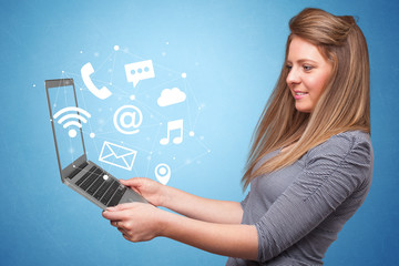 Woman holding laptop with online services symbols
