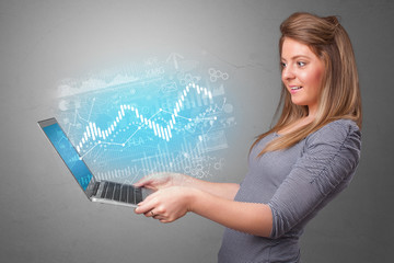 Woman holding laptop projecting financial information, diagrams and charts 
