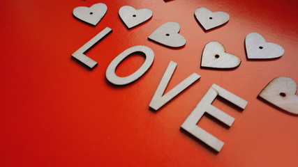Valentines Day background with red hearts and letters love - made of wood on red