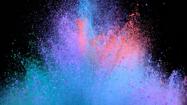 Super slowmotion shot of color powder explosions isolated on black background.