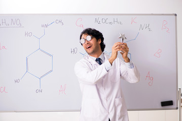 Young funny chemist in front of white board 