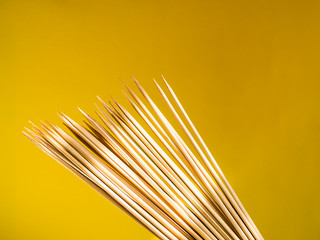 A lot of thin bamboo skewers for grill on a yellow background. Kitchen accessories for cooking kebab and barbecue, front view