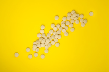 Scattering of pills on a yellow background. Natural food supplement brewer's yeast with vitamins and microelements. Flat lay, top view and copy space