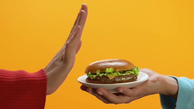 Female refusing high calorie burger offered by person, healthy eating habit