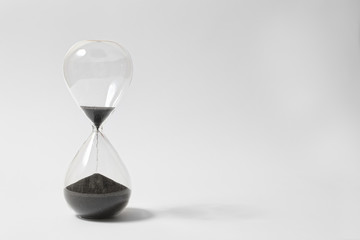 Hourglass On White Background, Running Out Of Time, Black Sand Flowing From Upper Bulb To Lower...