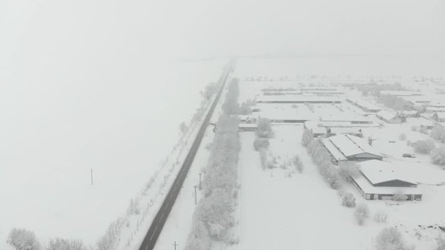 Drone 4K aerial footage of village covered with snow. White cloudy winter weather.