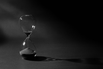 Hourglass On Black Background, Time Passing Concept, Black Sand Flowing Down From Upper Bulb To Lower Bulb Till Deadline
