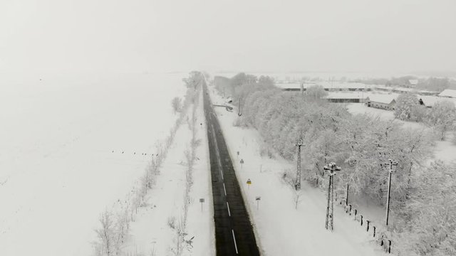Drone 4K aerial footage of village covered with snow. White cloudy winter weather.