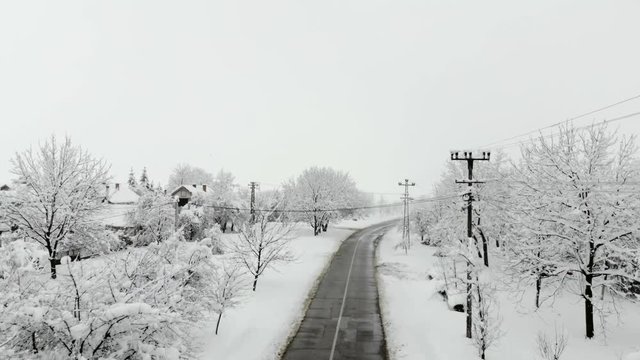 Drone 4K aerial footage of village covered with snow. White cloudy winter weather.