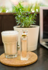 perfume and a glass of coffee stand wooden stand, perfume packaging on a wooden background, perfume and plants in a pot in the background