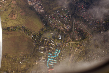 view from the plane to the Moscow region, top view of the fields, forests and houses with a blue roof, clouds