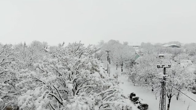 Drone 4K aerial footage of village covered with snow. White cloudy winter weather.
