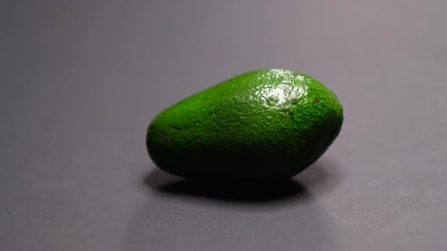 green avocado on black background, dancing shadows