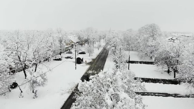 Drone 4K aerial footage of village covered with snow. White cloudy winter weather.