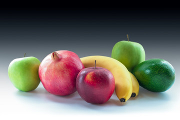 Apples, pomegranate, banana and avocado on a black and white background
