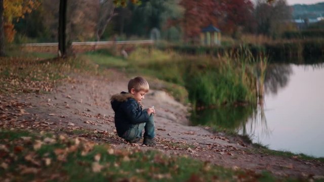 Picturesque autumn bokeh. Colorful landscape ,cute child boy todler plays in the park near the lake. Good childhood memories.