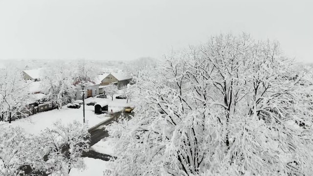 Drone 4K aerial footage of village covered with snow. White cloudy winter weather.