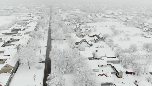 Drone 4K aerial footage of village covered with snow. White cloudy winter weather.