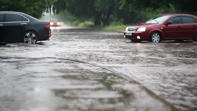 Car traffic on the flooded city street during heavy rain, heavy rainfall. Disaster flood, deluge. Water flow 