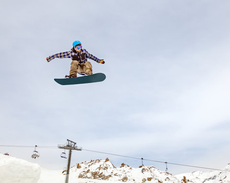 Jumping snowboarder in mountains on the snowboard