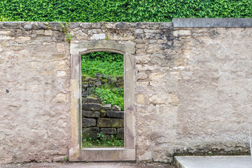 Wall in the park with passage and green hedge in the background