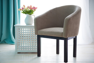 Beige chair on the background of the window. The interior of the apartment