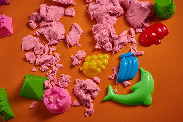 kinetic sand and toys. Top view. Close up. Orange background