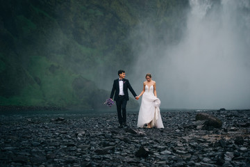 Young happy wedding couple walking on background of waterfall, outdoors - 243045914