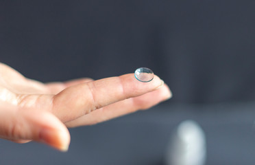 Woman hand holding eye lense on her finger