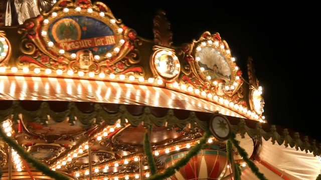 Nuremberg, Germany - December 1, 2018: Fascinating flashing lights dark night sky illumination of vintage merry go round fair carousel ferris wheel in christmas market