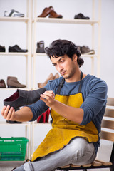 Young man repairing shoes in workshop 