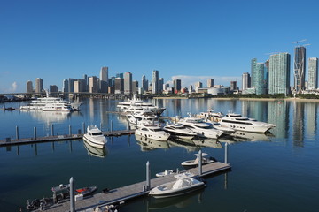 Miami, Florida 09-15-2018 The Island Gardens Deep Harbour super-yacht marina with the City of Miami reflected on calm Biscayne Bay in the background.