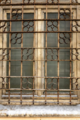 An old window with broken paint and decorative bars. Close-up photo.