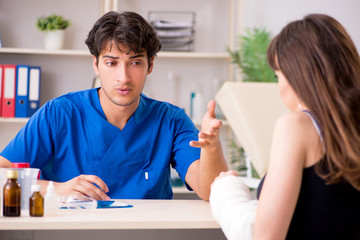 Obraz premium Young woman with bandaged arm visiting male doctor traumotologis