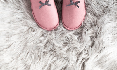 Fuzzy white fur carpet and soft comfortable home pink slippers. Slippers on carpet. Fluffy fake textile fur. Flat lay, top view, copy space