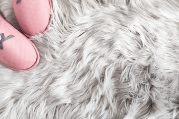 Fuzzy white fur carpet and soft comfortable home pink slippers. Slippers on carpet. Fluffy fake textile fur. Flat lay, top view, copy space