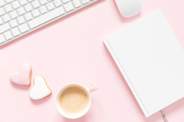Composition Valentine's Day. Female desktop сomputer keyboard, сup of coffee and ginger cookie in shape heart on pastel pink background. Valentine day concept, design.
