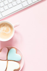 Composition Valentine's Day. Female desktop сomputer keyboard, сup of coffee and ginger cookie in shape heart on pastel pink background. Valentine day concept, design