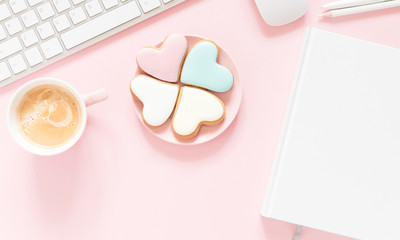 Composition Valentine's Day. Female desktop сomputer keyboard, сup of coffee and ginger cookie in shape heart on pastel pink background. Valentine day concept, design.