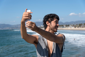 Happy young guy taking selfies on vacation at the beach