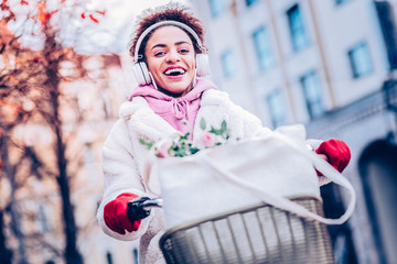 Positive delighted international girl keeping hands on handle bar