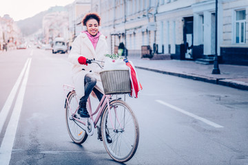 Positive delighted female person riding her bicycle