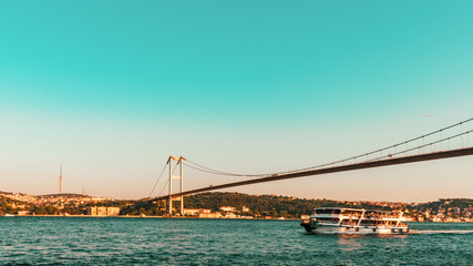 Fototapeta na wymiar Bosporus bridge and ferry boat before sunset, Istanbul, Turkey