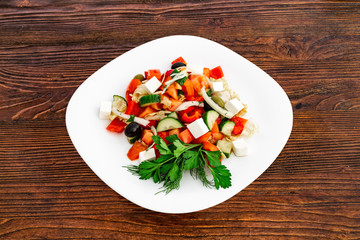 Greek salad of fresh cucumber, tomato, sweet pepper, lettuce, red onion, feta cheese and olives with olive oil. Healthy food, top view