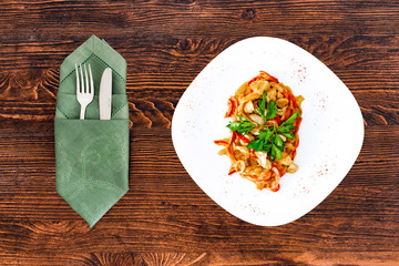 Chicken fricassee with mushrooms on a white plate with vegetables top view close-up with appliances