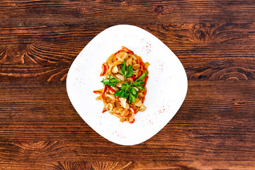 Chicken fricassee with mushrooms on a white plate with vegetables top view close-up