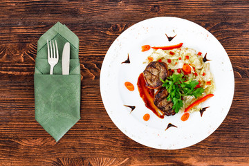Juicy beefsteak minion from medium rare beef with a sauce on a white plate with appliances