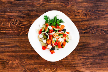 Greek salad of fresh cucumber, tomato, sweet pepper, lettuce, red onion, feta cheese and olives with olive oil. Healthy food, top view
