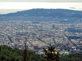 Barcelona from hill, showing buildings, mountains, sky and sea.